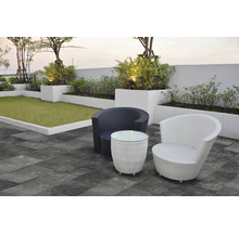 Scène avec deux fauteuils en rotin et une table sur une terrasse avec pelouse
