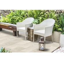 Terrasse avec deux fauteuils en rotin, une table en bois et une lanterne dans le jardin.