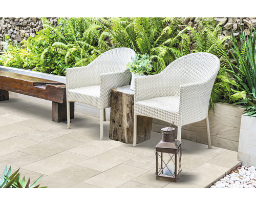Terrasse avec deux fauteuils en rotin, une table en bois et une lanterne dans le jardin.