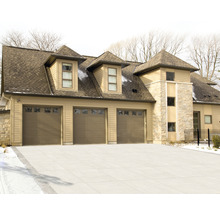 Vue d''une maison avec trois portes de garage et une façade en pierre