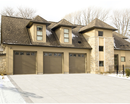 Vue d''une maison avec trois portes de garage et une façade en pierre