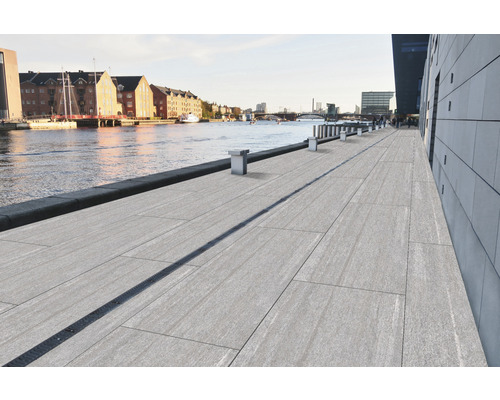 Vue sur une promenade riveraine avec dalles de sol et rigole de drainage