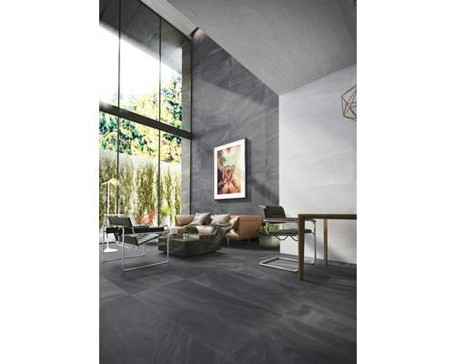 Espace de vie lumineux avec carrelage au sol, canapé, fauteuils et grande fenêtre