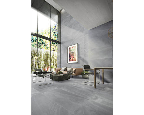 Salon moderne et lumineux avec carrelage de sol et mural gris aspect marbre, grandes fenêtres et mobilier élégant.