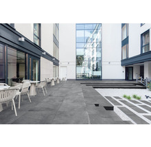 Aussenbereich mit Terrassenplatten, Tischen und Stühlen vor Gebäuden
