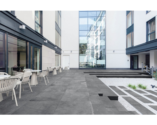 Aussenbereich mit Terrassenplatten, Tischen und Stühlen vor Gebäuden