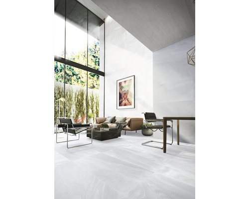 Salon lumineux avec carrelage, canapé, fauteuils et grande fenêtre