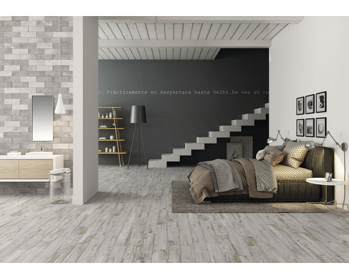 Pièce lumineuse avec plancher en bois, coin salle de bains avec lavabo et coin chambre avec lit et escalier