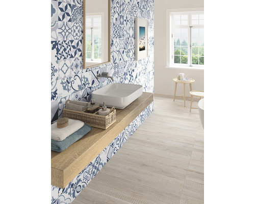 Helles Badezimmer mit blauen gemusterten Fliesen, Waschtisch und Holzfußboden