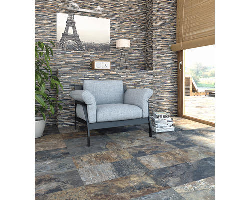 Salon avec parement mural aspect pierre, fauteuil et carrelage au sol