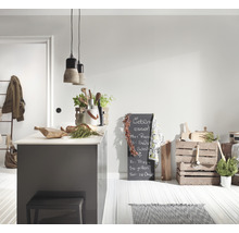 Cuisine claire avec îlot de cuisine, tabouret, tableau noir et caisses en bois comme décoration.
