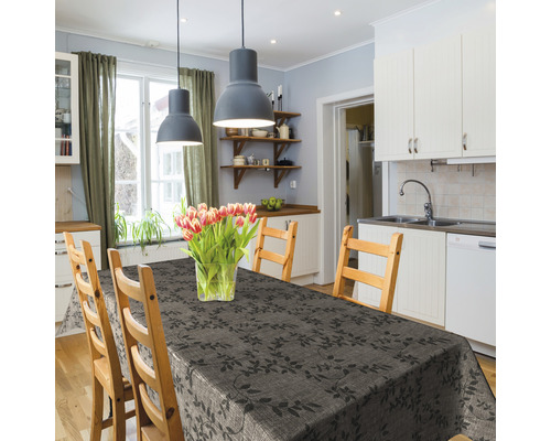 Table de salle à manger avec une nappe gris foncé à motif de feuilles dans une cuisine lumineuse.