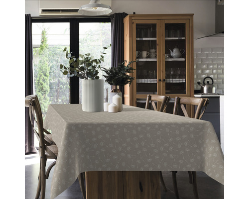 Table à manger avec une nappe à motifs, des vases de fleurs et des chaises dans une pièce lumineuse.