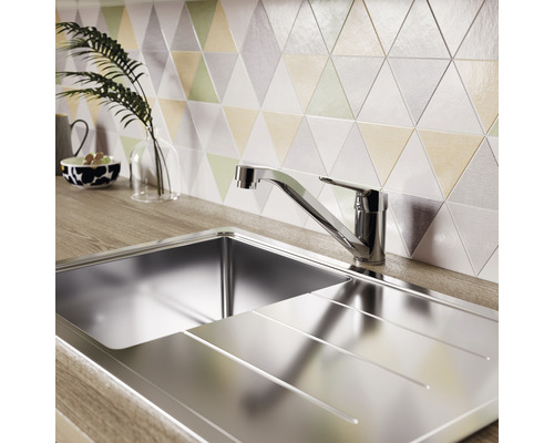 Évier en acier inoxydable avec égouttoir et robinet devant des carreaux muraux triangulaires