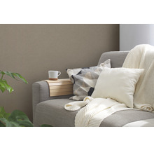 Canapé gris avec coussins, tasse et étagère en bois.