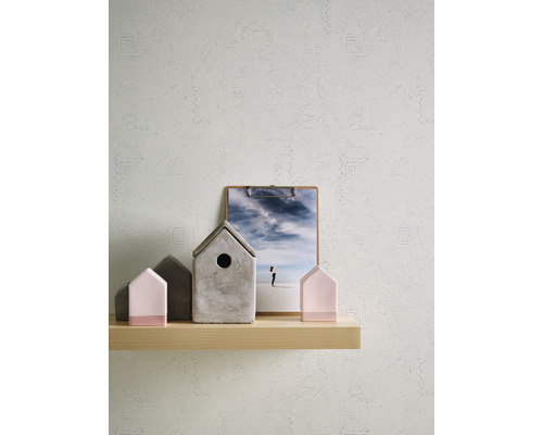 Regal mit Deko-Häusern, Bild und gemusterter Tapete im Hintergrund