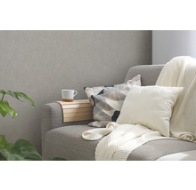 Graues Sofa mit Kissen und einem Getränkehalter aus Holz mit einer Tasse.