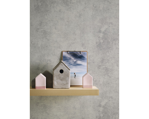 Maisons décoratives en béton et en bois sur une étagère devant un mur gris.