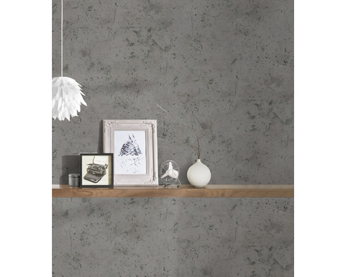 Wohnraumgestaltung mit grauer Betonoptik-Tapete, Holzregal, Bilderrahmen und Dekoration