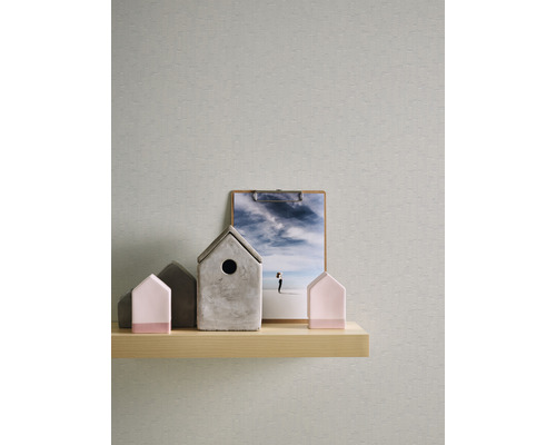 Maisons décoratives et une image sur une étagère en bois devant un papier peint.