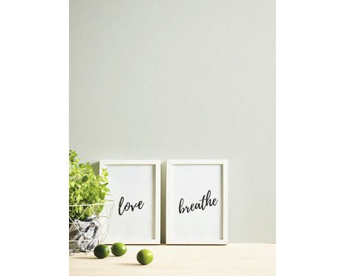 Dekorative Szene mit Pflanzen, Zitrusfrüchten und zwei gerahmten Kunstdrucken mit den Aufschriften Liebe und Atmen.