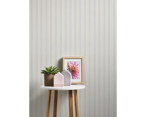Scène avec un papier peint rayé, une table, une plante d''intérieur et des objets décoratifs