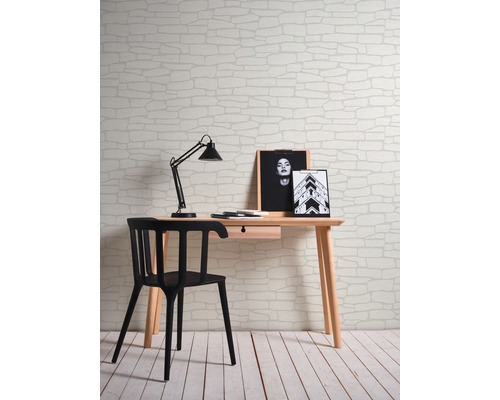 Scène avec bureau, chaise, lampe de bureau et un mur avec du papier peint à motif de pierre.