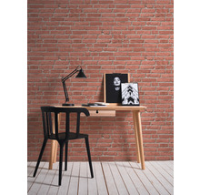 Bureau avec chaise, lampe et tableaux muraux devant un mur de briques