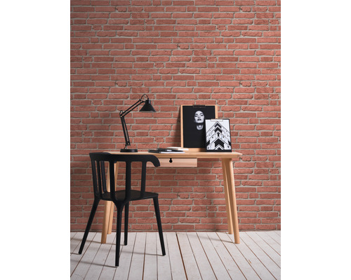 Bureau avec chaise, lampe et tableaux muraux devant un mur de briques