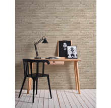 Bureau avec chaise, lampe et décoration devant un mur en briques