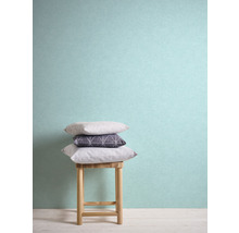 Stapel aus Kissen auf einem Holzschemel vor einer Wand