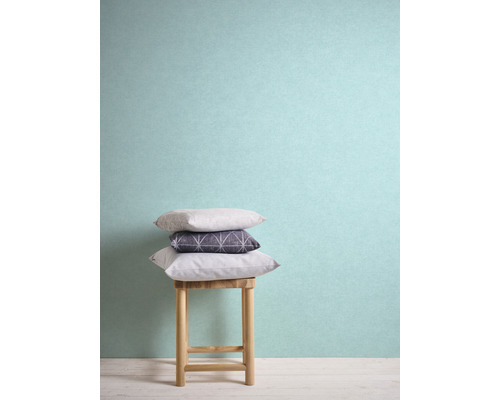 Stapel aus Kissen auf einem Holzschemel vor einer Wand