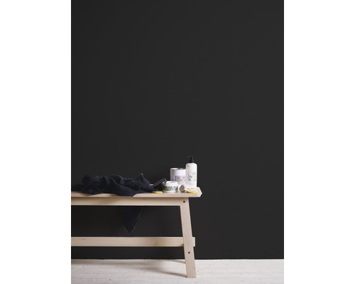 Peinture murale noire derrière une table en bois avec des articles de bain et une serviette.