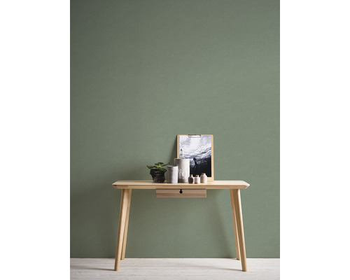 Holztisch mit Dekoration vor grüner Wand