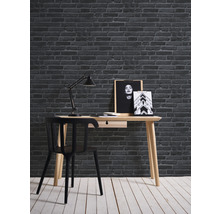 Bureau avec chaise, lampe et décoration murale devant un mur de briques