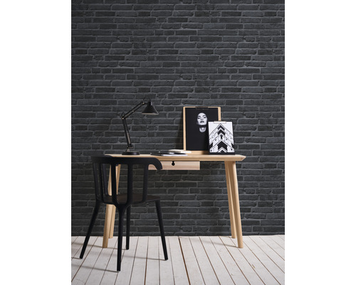 Bureau avec chaise, lampe et décoration murale devant un mur de briques