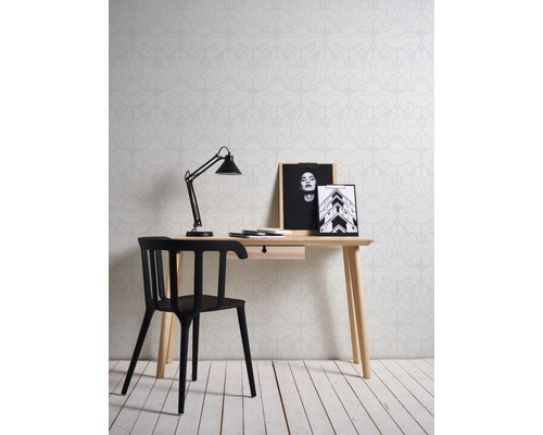 Büro mit Schreibtisch, Lampe, Stuhl und Bildern vor gemusterter Tapete
