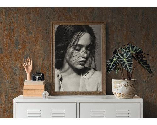 Scène décorative avec portrait encadré, plante en pot, modèle d''appareil photo et main en bois sur une armoire blanche.