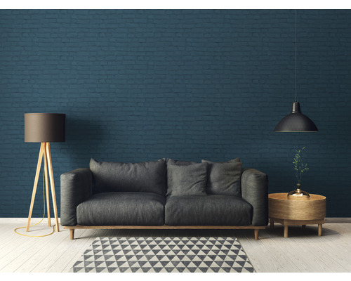 Wohnzimmer mit Sofa, Stehlampe, Beistelltisch und Hängelampe vor einer Ziegelwand