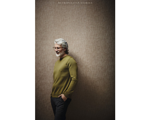 Homme portant un pull devant un mur avec du papier peint de la collection Metropolitan Stories