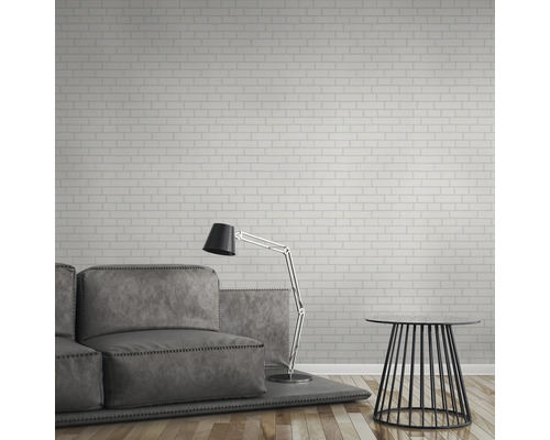 Salon avec canapé, lampadaire et table d''appoint devant un mur avec papier peint en briques.