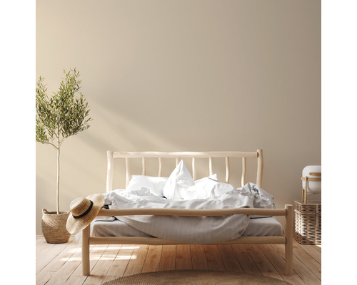 Helles Schlafzimmer mit Holzbett, Bettwäsche, Zimmerpflanze und Strohhut