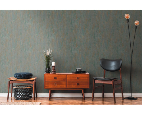 Wohnraum mit grün gemusterter Tapete, Kommode, Stuhl und Stehlampe