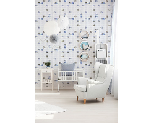 Kinderzimmer mit Kinderbett, Sessel und mit Schuhmotiven verzierter Tapete