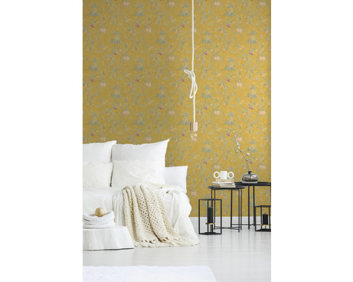 Schlafzimmer mit gelber gemusterter Tapete, Bett und Nachttischen.