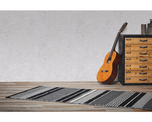 Une pièce avec un tapis rayé, une guitare et une commode.