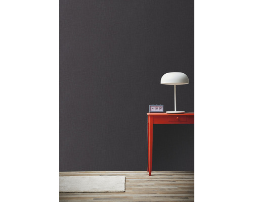 Mur gris décoratif avec table, lampe et tapis pour une ambiance d''habitation moderne.