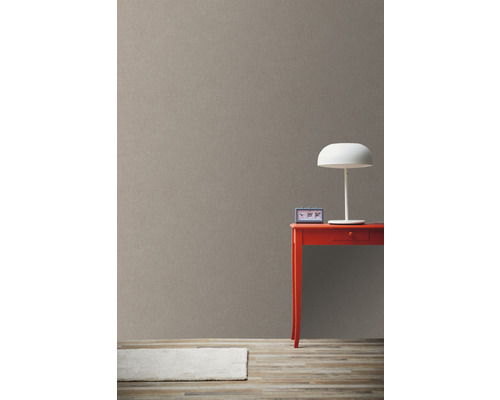 Vue claire d''une pièce avec du papier peint marron, une table rouge et une lampe blanche
