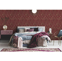 Ein Schlafzimmer mit einem Bett, einem Nachttisch und einer roten Tapete mit Muster