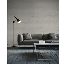Wohnzimmer mit grauem Sofa, Couchtisch und Stehlampe vor einer Ziegelwand